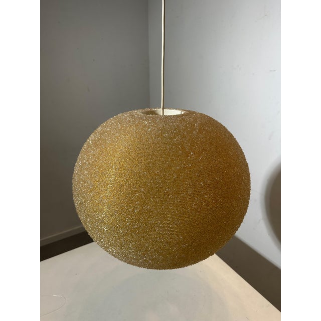 This stunning vintage pendant lamp features a beautifully textured amber glass shade with a spherical shape, offering a...