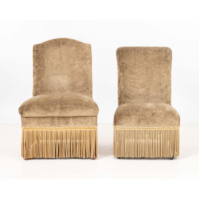 Associated Pair of Napoleon III Style Upholstered Slipper Chairs, tan velvet with braided fringe, smaller with front legs...