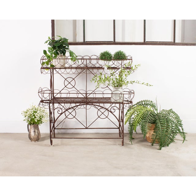 A charming French two-tier iron wirework baker's rack, plant stand, or pâtisserie display. The design features a defining...