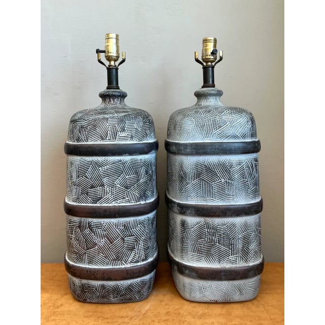Distinguished by bold tactile texturing and rich brutalist earth tones, this pair of mid-century modern ceramic table...