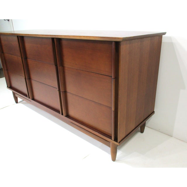 A Mid Century walnut nine drawer dresser chest with unique built in pulls blending in with the streamline style showing...
