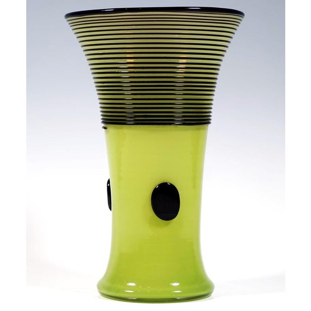 Mould-blown, funnel-shaped vessel on a flush base, with a flared rim, made of light green opal-coloured glass; black rim,...