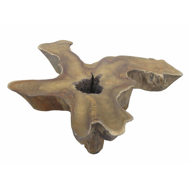This brown coffee table with graceful curvy edges and gorgeous wood grain is made of one single slab of teak wood. The...