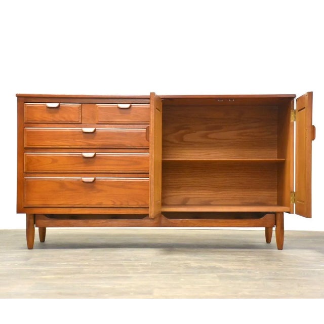 A mid century modern teak color chestnut sideboard credenza with four drawers and two doors that open up to shelving....