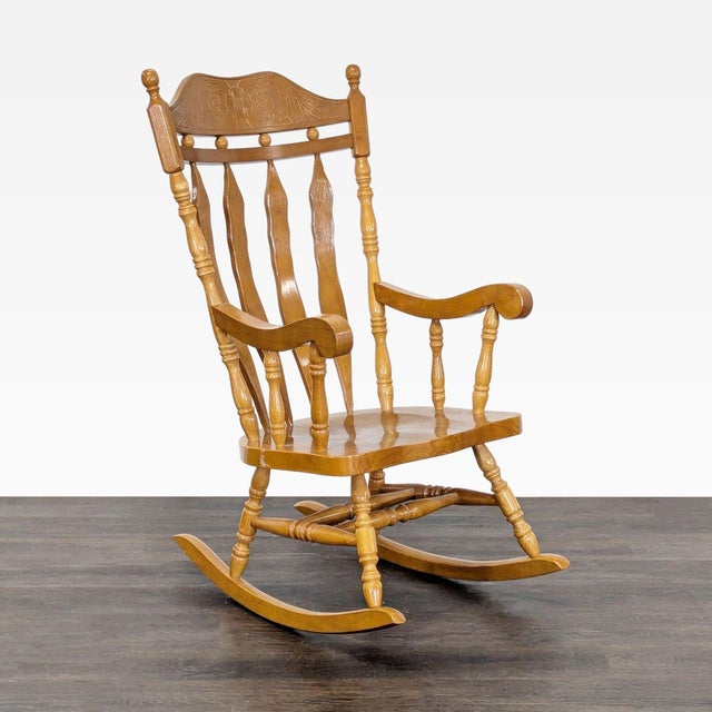 This sturdy wooden rocking chair features a warm finish and a beautiful carved design on the backrest. With turned spindle...