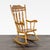 This sturdy wooden rocking chair features a warm finish and a beautiful carved design on the backrest. With turned spindle...