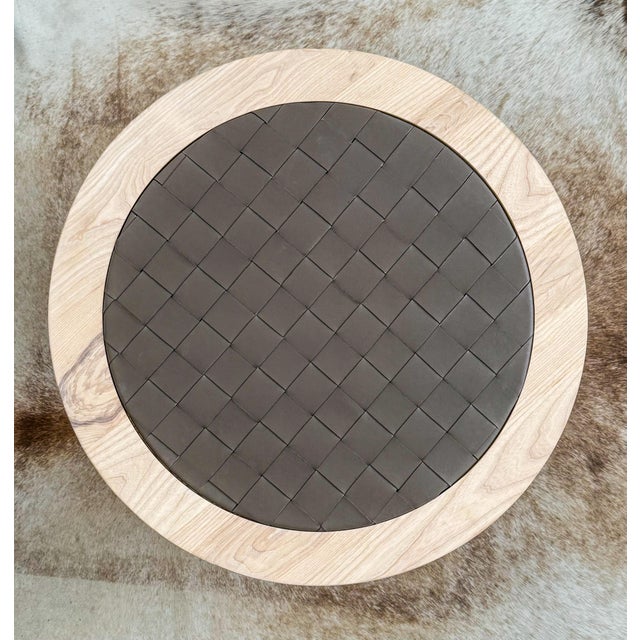 This custom, artisan-made round coffee table is crafted from solid maple wood and finished with a hand-woven genuine...