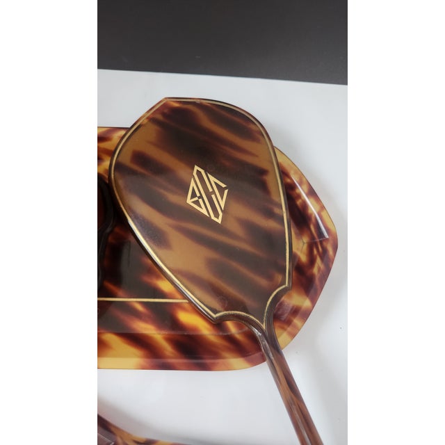 A charming Art Deco vanity dressing set by Pyralin, finished in a tortoiseshell-patterned celluloid and accented with fine...