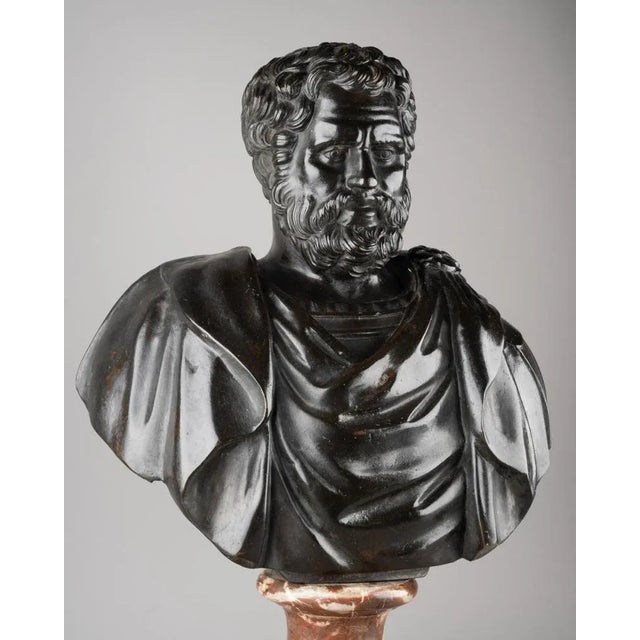An chiselled and black-patinated bronze bust depicting a Roman emperor or general dressed with a chlamys held in place by...