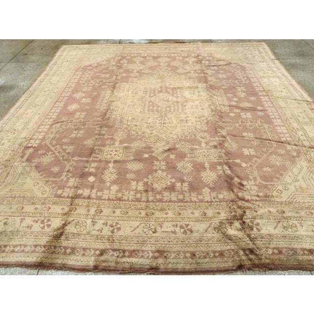 An antique Turkish Oushak room size carpet. A stepped ivory cartouche-form medallion is set on a soft medium brownfield...