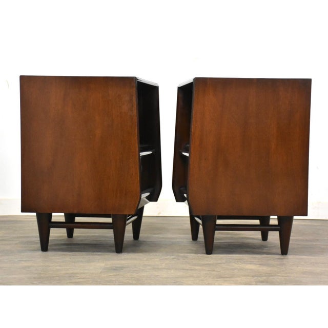 A pair of mid century modern mahogany two drawer nightstands with sculpted pulls. 20” wide. 17.25” deep. 26.25” tall.