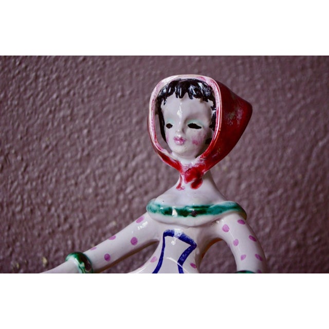 Full of character, this small glazed earthenware ring holder depicts a female figure whose flared skirt forms the...