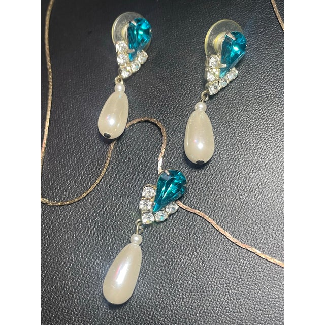 This mid-century vintage demi-parure set features striking earrings of pear-cut focal rhinestones in a deep teal or...