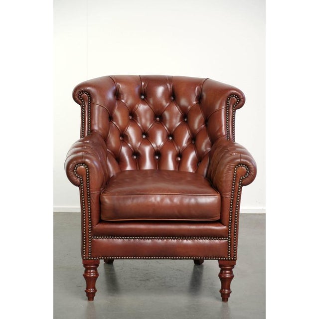 This cognac-colored cowhide Chesterfield armchair is crafted in a timeless English style and is of high quality. The...
