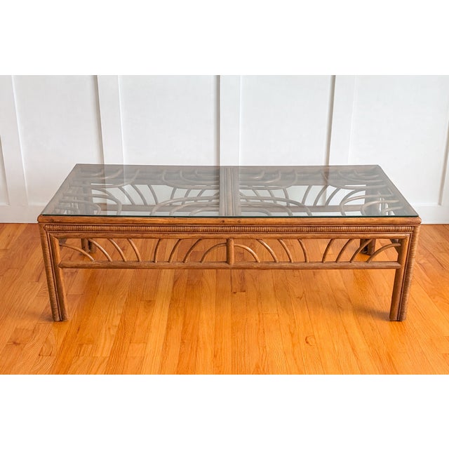 Elevate your space with this gorgeous vintage rattan coffee table with glass top. The wrapped rattan frame features...