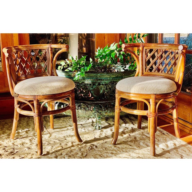 Palm Beach chic pair of late 20th century vintage lattice back rattan bamboo horseshoe chairs. Original upholstery in a...
