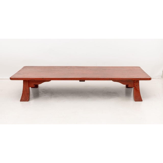 Japanese Red and Black Lacquered Low Table, with carved apron on four inverse tapered legs. 12.5" H x 71.5" W x 35" D....