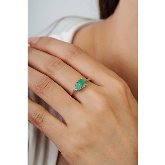 The Modernist 0.98 Ct Natural Emerald Pear & Octagon Toi et Moi Ring features 0.98 carats of natural emeralds set in 925...
