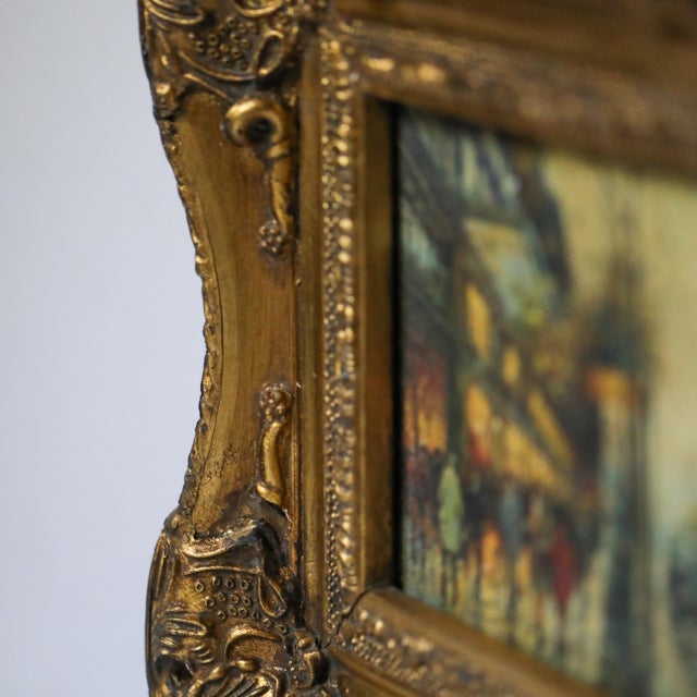 Small early 20th century oil on board painting depicting a lively European street scene with pedestrians, illuminated...