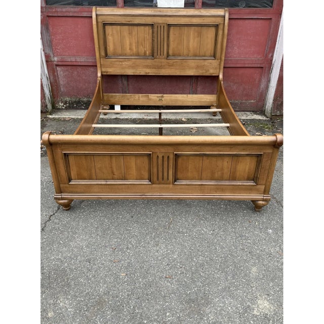 A vintage Ethan Allen queen-size sleigh bed frame with a planked design and wide fluting on the headboard and low...