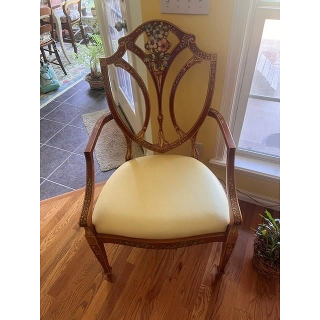 This elegant vintage armchair features a classic shield-back design adorned with intricate hand-painted floral motifs in...