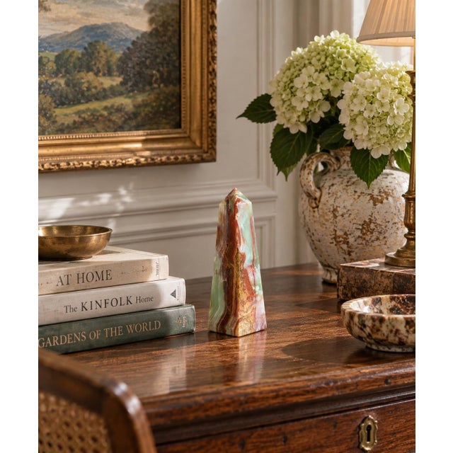A beautifully proportioned marble obelisk in richly veined shades of green, brown, cream, and tan. The sculptural...