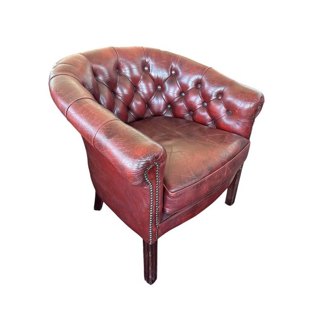 Classic Chesterfield-style club chair upholstered in deep oxblood red leatherette with rich patina and deep button-...
