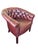 Classic Chesterfield-style club chair upholstered in deep oxblood red leatherette with rich patina and deep button-...