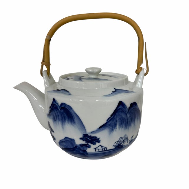 Vintage Japanese porcelain teapot, featuring a blue and white painted landscape design and a woven bamboo handle. Design:...