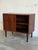 This compact storage piece features a clean rectilinear form with smooth sliding doors. Its minimalist silhouette...