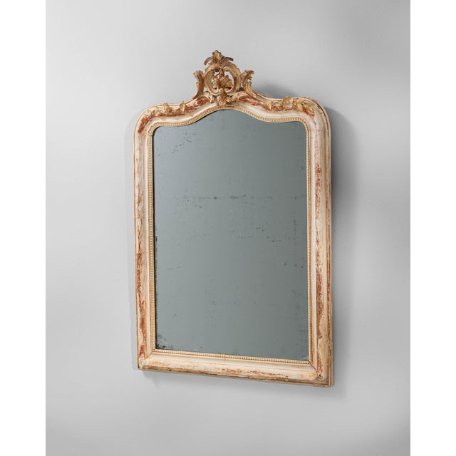 This 19th century French mirror features a gracefully carved wooden frame adorned with Rococo-inspired scrollwork and...