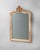 This 19th century French mirror features a gracefully carved wooden frame adorned with Rococo-inspired scrollwork and...