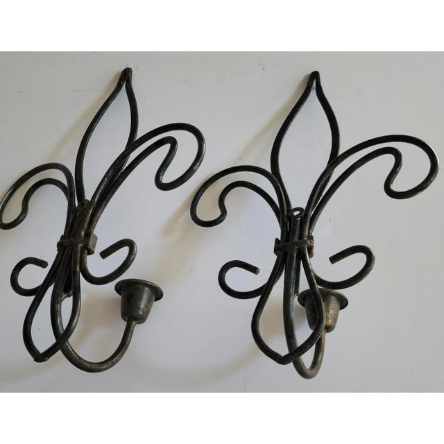 This pair of wrought iron fleur-de-lis candle sconces have a vintage patina with black/bronze finish. They would be great...