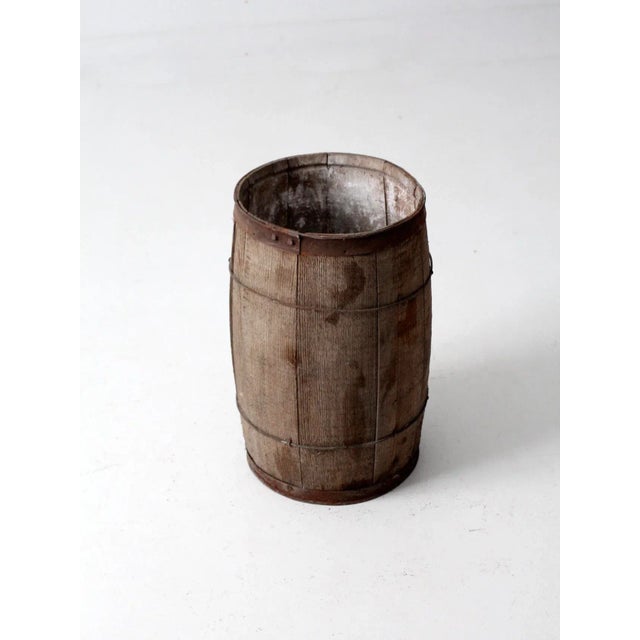This is an antique primitive barrel. The rustic wooden keg features wood slats and metal banding.