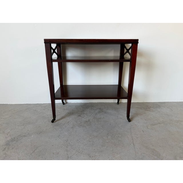 Elegant 1960s French Hollywood Regency three-tier side table crafted in rich mahogany with a warm, deep finish. Features a...