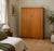 A 1960s mid-century double wardrobe in warm teak veneer, featuring clean lines, wooden handles and subtle segmented...