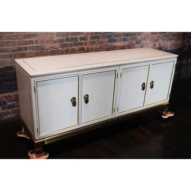 Stunning and rare cream colored faux leather wrapped buffet (sideboard). There are brass inlays to the top of the buffet...