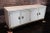 Stunning and rare cream colored faux leather wrapped buffet (sideboard). There are brass inlays to the top of the buffet...