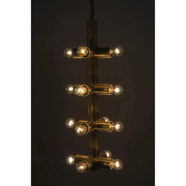 This stripped-down hardwired chandelier features 16 low watt exposed bulbs in a simple metal inner structure for an...