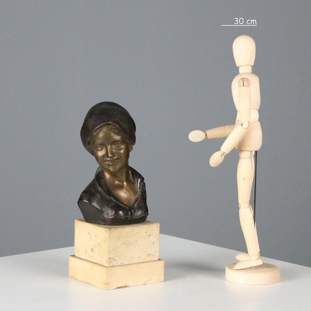 Bronze half-bust depicting a commoner wearing a headscarf. Double marble base. Signature engraved on the back. This piece...