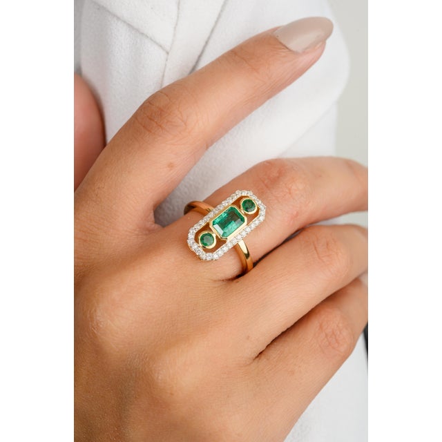 This modern antique ring features a captivating three-stone emerald axis design, elegantly set in 18k yellow gold. The...