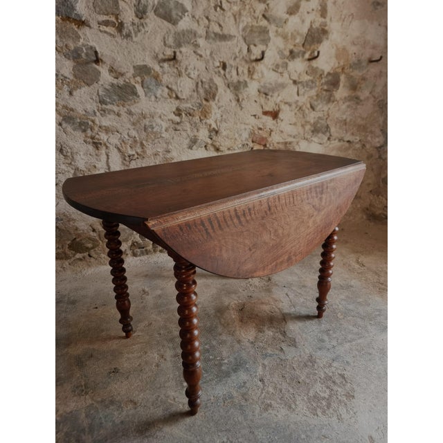 French walnut drop-leaf dining table dating from approximately 1880–1920. The table features folding leaves on both sides,...