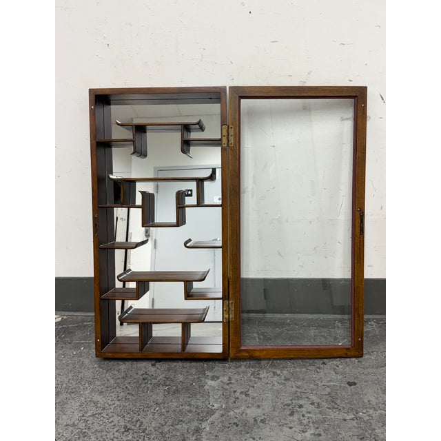 Design Plus Gallery presents a Vintage Chinoiserie Wood Wall Mount Curio Cabinet. This vintage curio cabinet has a carved...