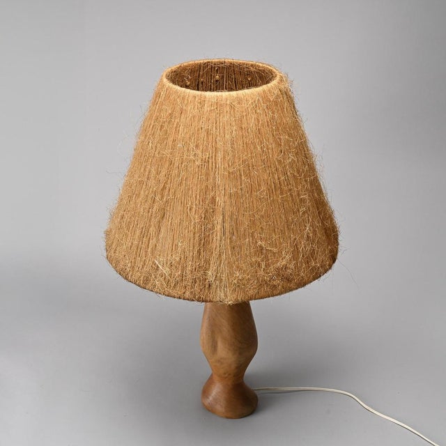 Table lamp made in France around 1960. The turned wood base has a slender, organic silhouette, resting on a discreet...