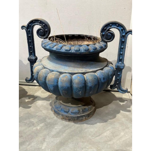 One of two pairs available. These double handled urns of French painted cast iron are of bulbous, semi-lobed form, the...