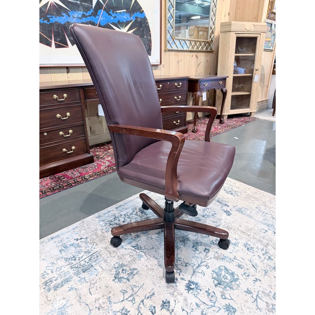 A distinguished Hancock & Moore executive desk chair upholstered in rich burgundy leather with a refined tailored...