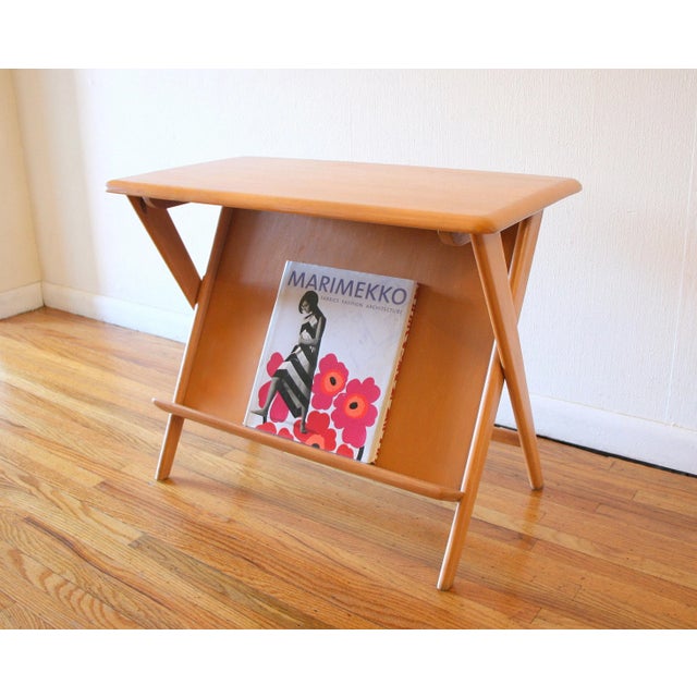 This is a beautiful mid century modern side end table by Heywood Wakefield, circa 1950s. It has a built in magazine rack...