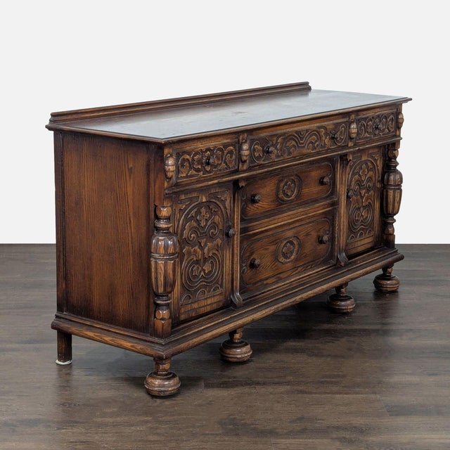 This vintage sideboard features detailed carved designs and a rich wood finish. It offers plenty of storage with two large...