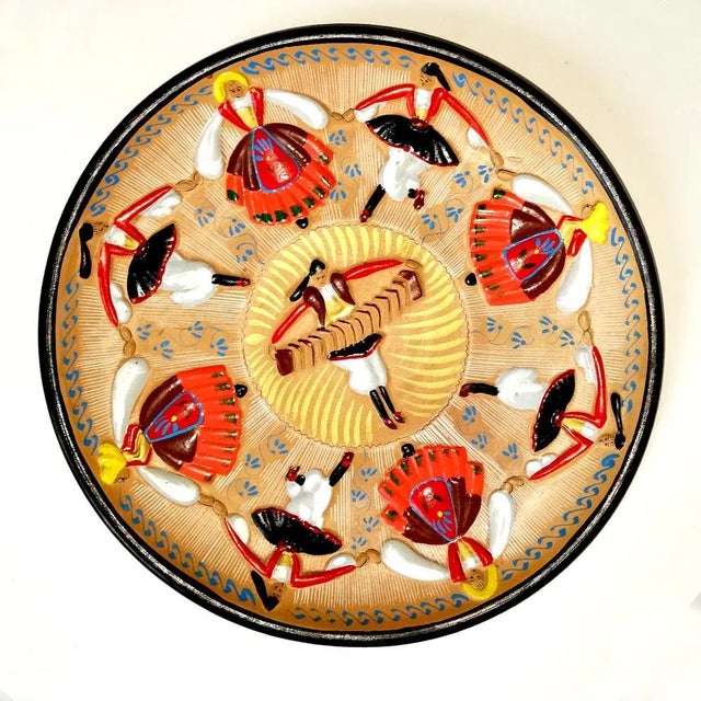 This polychrome ceramic plate features a regional dance decoration in relief. It is signed and hand painted by Enzo Loi.