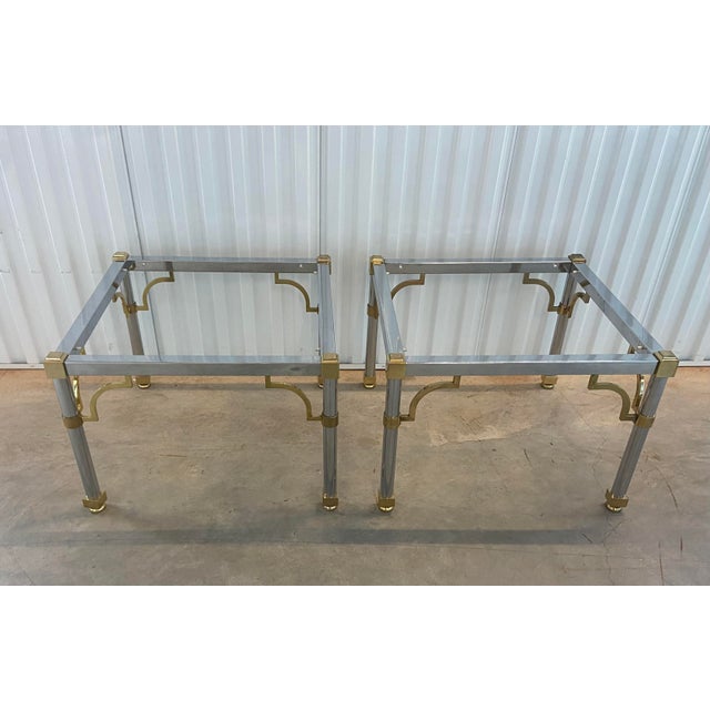 A fabulous pair of mid century chrome and brass glass-top side tables in the style of Maison Jansen. Single-layered glass...